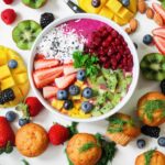 Cuenco de frutas rodeado de fruta variada